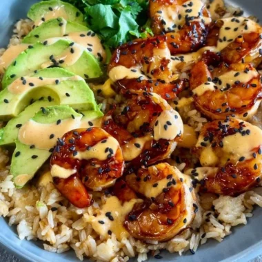 Delicious teriyaki shrimp rice bowl garnished with vegetables and sesame seeds.