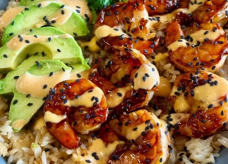 Delicious teriyaki shrimp rice bowl garnished with vegetables and sesame seeds.