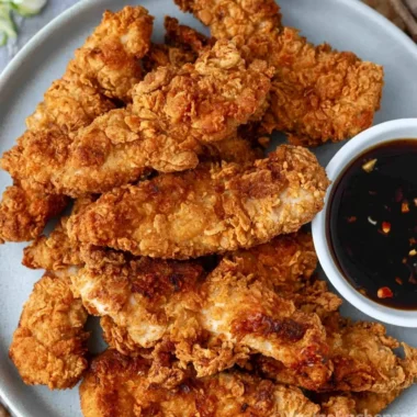 Crispy honey garlic chicken tenders plated with sauce and garnishments