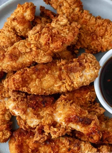 Crispy honey garlic chicken tenders plated with sauce and garnishments