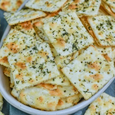A close-up of Dill Pickle Saltine Crackers with a jar of pickles