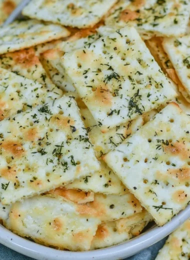 A close-up of Dill Pickle Saltine Crackers with a jar of pickles