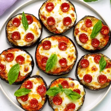Plated mini eggplant pizzas topped with cheese and toppings