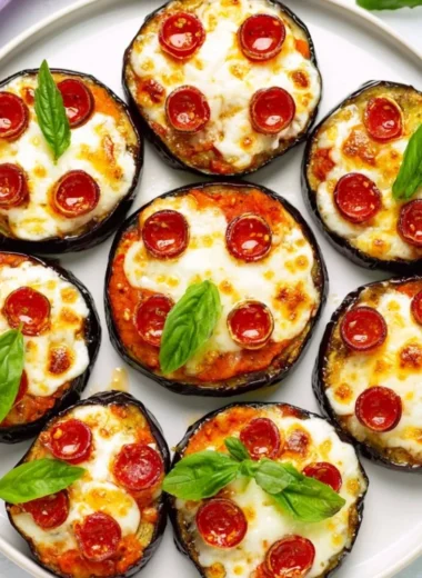 Plated mini eggplant pizzas topped with cheese and toppings