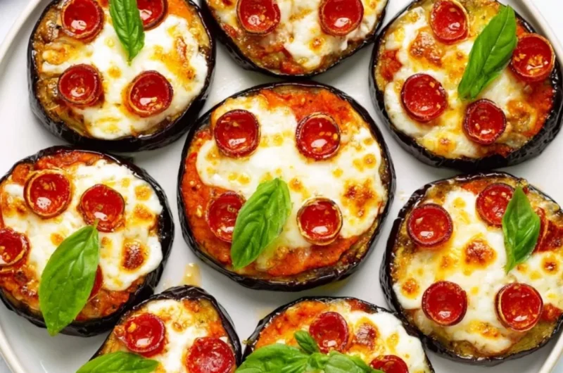 Plated mini eggplant pizzas topped with cheese and toppings