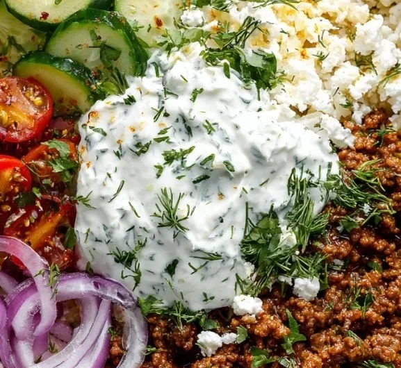 Greek Ground Beef Bowl topped with Tzatziki sauce and fresh vegetables