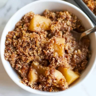 Healthy breakfast apple crumble served in a bowl with fresh apples and oats