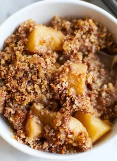 Healthy breakfast apple crumble served in a bowl with fresh apples and oats