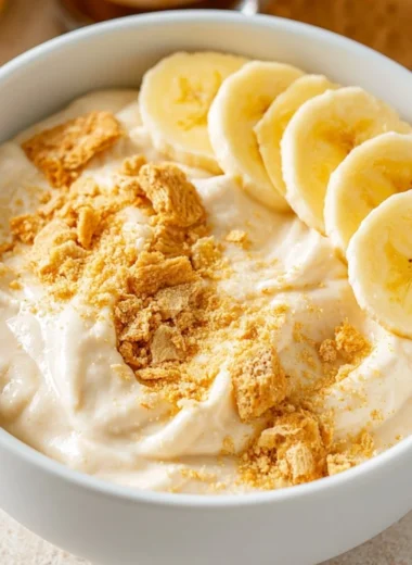 High protein banana pudding bowl topped with banana slices and whipped cream