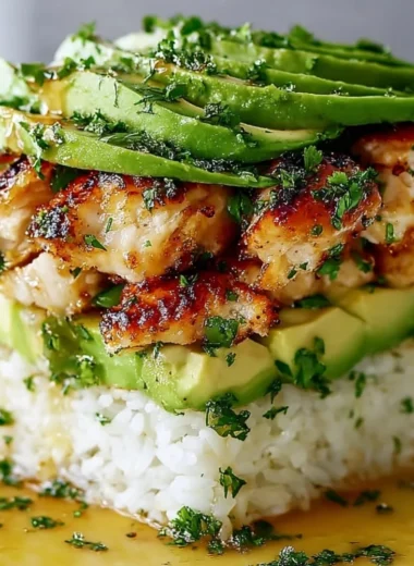 Honey Lime Chicken Avocado Rice Stack garnished with fresh herbs.