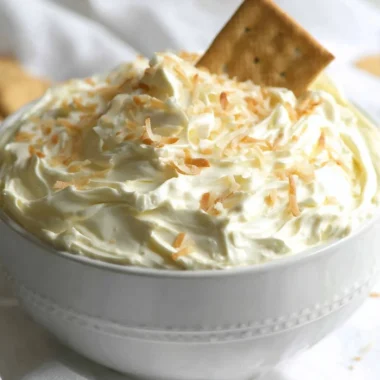 No Bake Coconut Cream Pie Dip served in a bowl with a spoon and coconut flakes