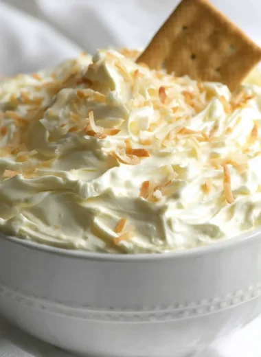 No Bake Coconut Cream Pie Dip served in a bowl with a spoon and coconut flakes