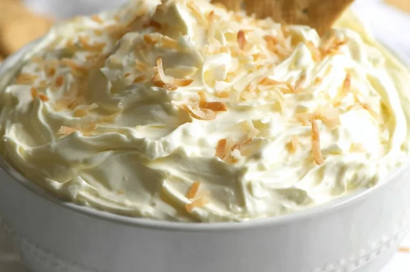 No Bake Coconut Cream Pie Dip served in a bowl with a spoon and coconut flakes