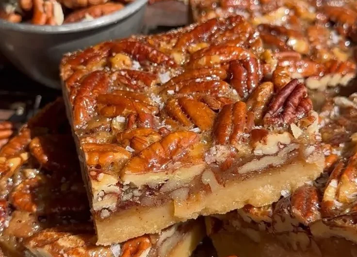 Delicious pecan pie bars topped with pecans and caramel sauce.