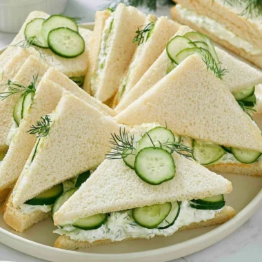 Tuna sandwich topped with fresh tomato slices on a plate