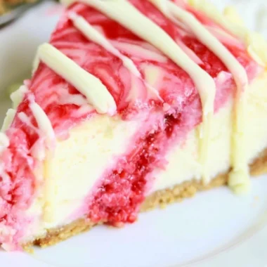White Chocolate Raspberry Swirl Cheesecake topped with fresh raspberries