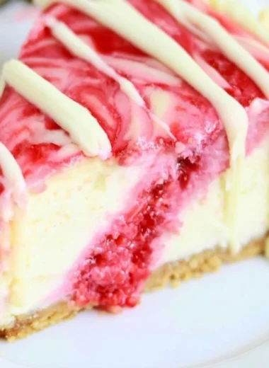 White Chocolate Raspberry Swirl Cheesecake topped with fresh raspberries