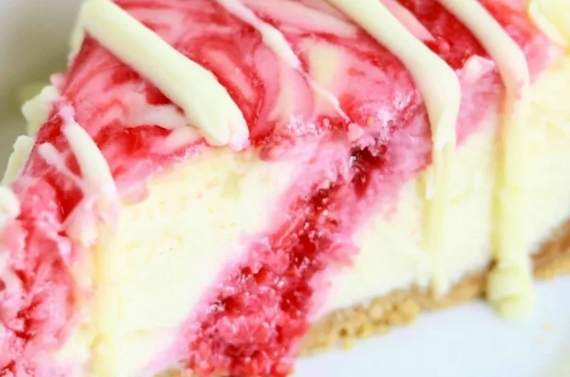 White Chocolate Raspberry Swirl Cheesecake topped with fresh raspberries