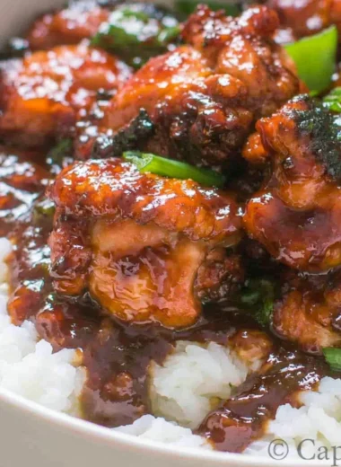 Delicious Mongolian Chicken stir-fry served over rice with vegetables.