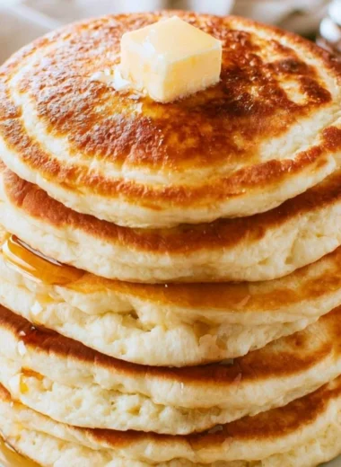 Stack of fluffy pancakes drizzled with syrup and topped with fresh berries