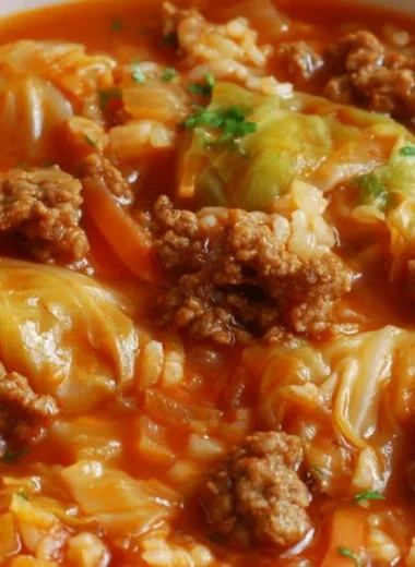 Bowl of homemade cabbage roll soup topped with herbs and served with crusty bread