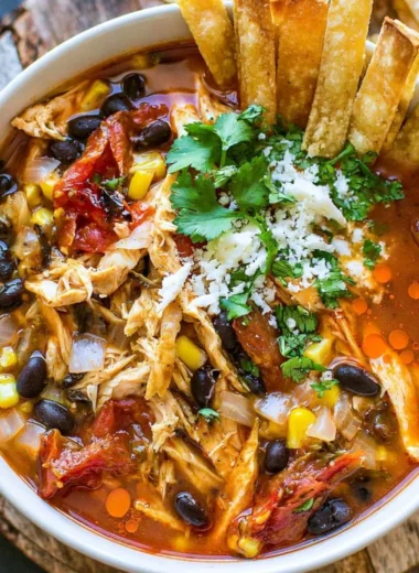 Bowl of cozy easy tortilla soup topped with tortilla strips and avocado.