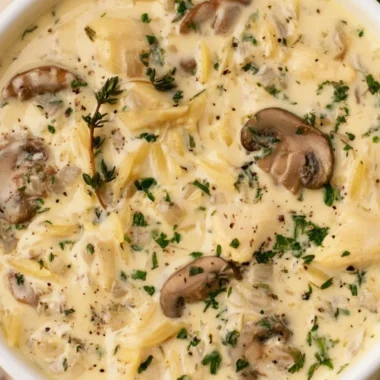 Bowl of creamy chicken soup with Boursin cheese, garnished with herbs.