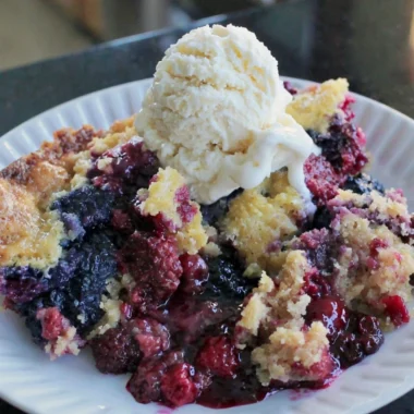 Easy blackberry dump cake topped with fresh berries and whipped cream