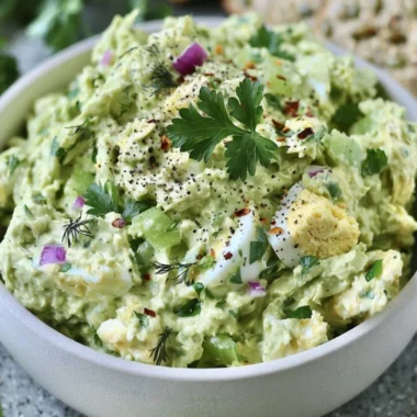 Herby avocado egg salad served in a bowl with fresh herbs and eggs.