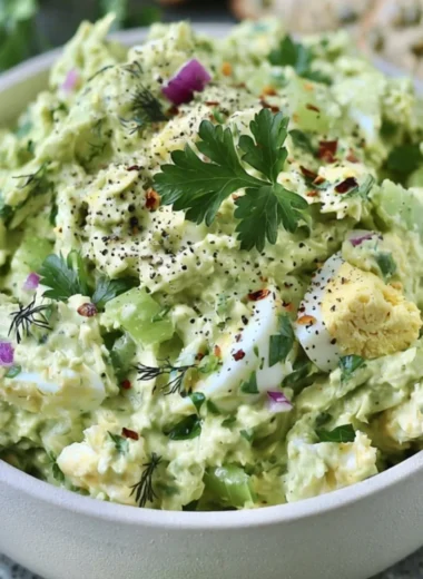 Herby avocado egg salad served in a bowl with fresh herbs and eggs.