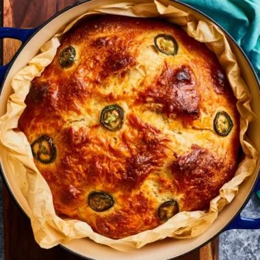 Jalapeño Cheddar Dutch Oven Bread in a rustic setting with herbs