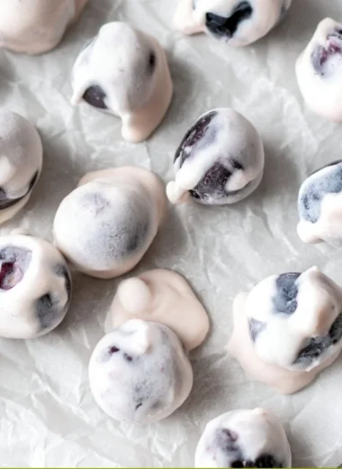 A bowl of yogurt covered blueberries, a healthy and sweet snack option.