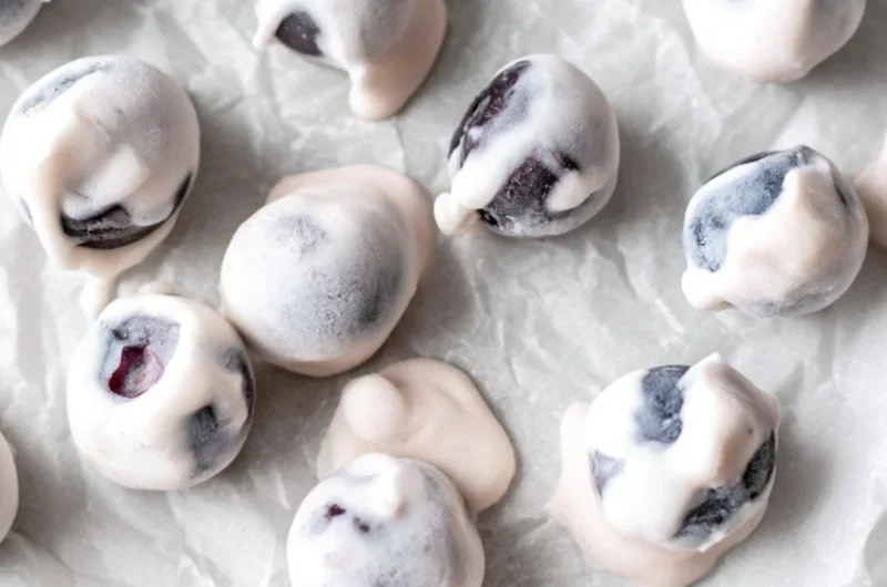 A bowl of yogurt covered blueberries, a healthy and sweet snack option.