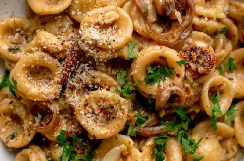 A bowl of caramelized onion pasta garnished with herbs and cheese, perfect for weeknight dinners.