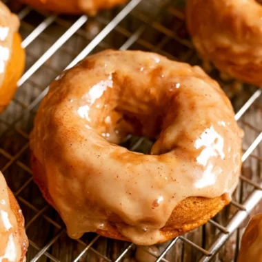 Cozy vegan pumpkin donuts served on a plate, topped with spices and icing.
