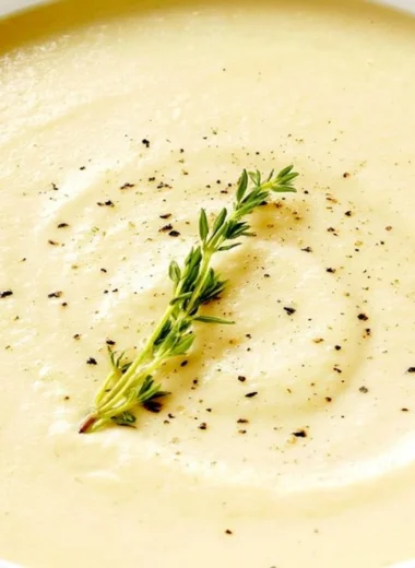 Bowl of creamy cauliflower soup topped with fresh herbs