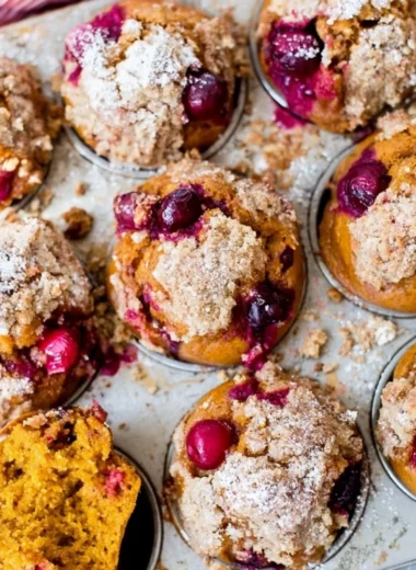 Pumpkin Spice Cranberry Muffins displayed on a rustic wooden table.